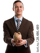 Young happy business man holding piggybank over white background. Стоковое фото, фотограф Kirill Kedrinskiy / Ingram Publishing / Фотобанк Лори