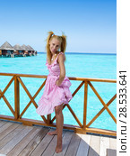 Young beautiful girl stands in pink sundress on sundeck of villa on water, Maldives. Стоковое фото, фотограф Куликов Константин / Фотобанк Лори