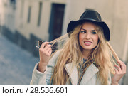 Portrait of beautiful young woman playing with her curly hair and smiling in urban background. Girl wearing jacket and hat. Стоковое фото, фотограф Javier Sánchez Mingorance / Ingram Publishing / Фотобанк Лори