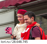 На Никольской улице в Москве футбольные фанаты знакомятся и фотографируются друг с другом. Болельщик из Туниса держит на руках девочку-россиянку. Чемпионат мира по футболу FIFA 2018, Россия. Редакционное фото, фотограф Наталья Николаева / Фотобанк Лори