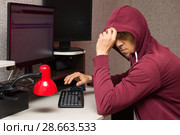 Интернет тролль у компьютера. Агрессивный мужчина в капюшоне что-то печатает читая форум. Стоковое фото, фотограф Лариса Капусткина / Фотобанк Лори