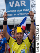 Футбольный болельщик в форме судьи Чемпионата мира по футболу FIFA 2018 держит плакат с надписью "VAR" (Video assistant referee) у стадиона Лужники в городе Москве перед финальным матчем чемпионата, Россия. Редакционное фото, фотограф Николай Винокуров / Фотобанк Лори
