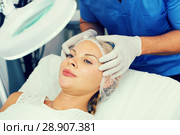 Specialist is analysing skin of female patient with using magnification before the procedure. Стоковое фото, фотограф Яков Филимонов / Фотобанк Лори