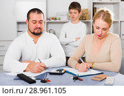 Parents calculating family budget while son standing behind. Стоковое фото, фотограф Яков Филимонов / Фотобанк Лори