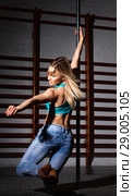 Sexy young woman in ripped jeans practicing pole dancing in dark fitness studio. Стоковое фото, фотограф Яков Филимонов / Фотобанк Лори