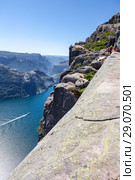 Вид на Люсе-фьорд с паромом из городка Lyseboth. Туристы на скале Prekestolen. Кафедра проповедника, Форсанн, Норвегия (2018 год). Стоковое фото, фотограф Кекяляйнен Андрей / Фотобанк Лори