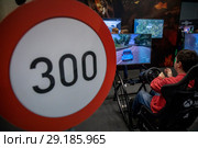 Молодой парень играет в гоночную игру Forza Horizon 4 на выставке Игромир в выставочном центре Крокус Сити города Москвы, Россия (2018 год). Редакционное фото, фотограф Николай Винокуров / Фотобанк Лори