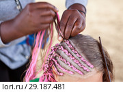 Afro American hairdresser made plaits in African style for young Caucasian girl, close-up. Стоковое фото, фотограф Кекяляйнен Андрей / Фотобанк Лори