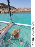 Woman relaxing on a summer sailing cruise,lying in hammock of luxury catamaran near picture perfect white sandy beach on Spargi island in Maddalena Archipelago, Sardinia, Italy. Стоковое фото, фотограф Matej Kastelic / Фотобанк Лори