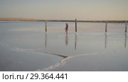 Slim sexy girl enjoying sunset, walks between wooden salt pillars of a salt lake. Стоковое видео, видеограф Ирина Мойсеева / Фотобанк Лори