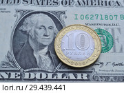 Российская металлическая монета 10 рублей крупным планом на фоне Американской банкноты  достоинством 1 доллар.Портрет Президента США Джорджа Вашингтона (2018 год). Редакционное фото, фотограф александр афанасьев / Фотобанк Лори