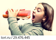 Hungry girl with open mouth and with giant bread and sausage sandwich on white background. Стоковое фото, фотограф Элина Гаревская / Фотобанк Лори