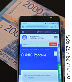 Экран смартфона сайтом Федеральной налоговой службы и российские деньги (2018 год). Редакционное фото, фотограф Цибаев Алексей / Фотобанк Лори