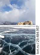 Baikal Lake in winter. Strait Small Sea (Maloe More). Beautiful smooth ice with cracks near the stone island of Borga-Dagan on the background of cumulus clouds. Стоковое фото, фотограф Виктория Катьянова / Фотобанк Лори