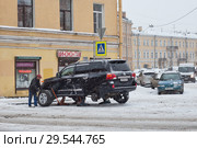 Мужчина меняет колеса на шиномонтаже во время снегопада в Санкт-Петербурге (2017 год). Редакционное фото, фотограф Евгений Кашпирев / Фотобанк Лори