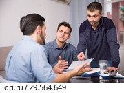 Three men worriedly discussing documents. Стоковое фото, фотограф Яков Филимонов / Фотобанк Лори