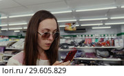 Woman Using the Phone in the Store. Стоковое видео, видеограф Ekaterina Demidova / Фотобанк Лори