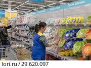 Женщина-работник сетевого супермаркета меняет выставляет товар - столовую посуду (2018 год). Редакционное фото, фотограф Игорь Тарасов / Фотобанк Лори