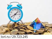 Стеклянная пирамида и настольные часы лежат на куче десятирублевых российских монетах. Стоковое фото, фотограф Иванов Алексей / Фотобанк Лори