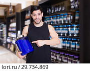 Attractive sport man seller demostration different sport nutrition products. Стоковое фото, фотограф Яков Филимонов / Фотобанк Лори