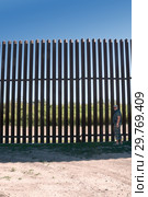 A man stands near a new iron Mexico–United States barrier  in the countryside Texas (2019 год). Стоковое фото, фотограф Ирина Кожемякина / Фотобанк Лори