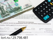 Время платить налоги. Российские купюры, шариковая ручка, калькулятор и незаполненный бланк налоговой декларация на вменённый доход. Стоковое фото, фотограф Игорь Низов / Фотобанк Лори