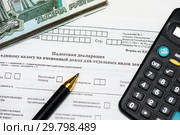 Оплата налогов. Российские деньги, шариковая ручка, калькулятор и незаполненный бланк налоговой декларация на вменённый доход. Стоковое фото, фотограф Игорь Низов / Фотобанк Лори