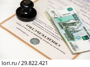 Печать организации и пачка российских денег лежат на свидетельстве индивидуального предпринимателя. Стоковое фото, фотограф Игорь Низов / Фотобанк Лори