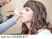 Artist applying makeup, girlfriend using brush for eyes colouring, two women. Стоковое фото, фотограф Кекяляйнен Андрей / Фотобанк Лори