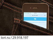 Сайт "Вконтакте" на экране мобильного телефона. Смартфон лежит в заднем кармане джинсовых штанов (2019 год). Редакционное фото, фотограф E. O. / Фотобанк Лори