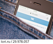 Сайт "Вконтакте" на экране телефона. Смартфон лежит в кармане джинсовых штанов (2019 год). Редакционное фото, фотограф E. O. / Фотобанк Лори
