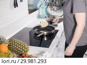 Cooking. Young woman making pancakes on the kitchen. Fresh fruits on the table. Стоковое фото, фотограф Константин Шишкин / Фотобанк Лори