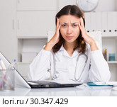 Upset practicioner girl is working with documents and laptop. Стоковое фото, фотограф Яков Филимонов / Фотобанк Лори