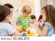 Teacher teaches kids modeling clay in playroom at kindergarten. Стоковое фото, фотограф Оксана Кузьмина / Фотобанк Лори