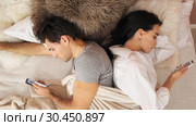 Married couple lies back to back in bed with mobile phones. Slow motion. Стоковое видео, видеограф Denis Mishchenko / Фотобанк Лори