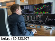 Stock trader looking at computer screens in trdading office. Стоковое фото, фотограф Matej Kastelic / Фотобанк Лори