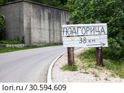 Деревянный указатель с направлением и расстоянием до города Подгорица в сельской местности на сельской дороге. Черногория (2016 год). Стоковое фото, фотограф Кекяляйнен Андрей / Фотобанк Лори
