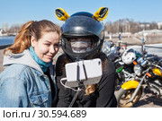 Молодые женщины мотоциклистки делают селфи с помощью мобильного телефона и раздвижного монопода. Стоковое фото, фотограф Кекяляйнен Андрей / Фотобанк Лори