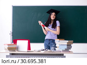 Female graduate student in front of green board. Стоковое фото, фотограф Elnur / Фотобанк Лори