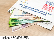 Конверт со счетом и деньги на оплату квартиры и услуг ЖКХ. Единый платежный документ, счет за жилищно-коммунальные услуги Мособлеирц (2019 год). Редакционное фото, фотограф Кузин Алексей / Фотобанк Лори