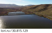 Flying over a hilly rural landscape with a winding road and fish ponds. Стоковое видео, видеограф Сергей Пристяжнюк (Serg Zastavkin) / Фотобанк Лори