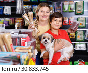 Cheerful woman with preteen son buying dog treats and chews in store to reward their precious pup. Стоковое фото, фотограф Яков Филимонов / Фотобанк Лори