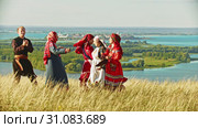 People in traditional russian clothes dancing on the field by the music from balalaika. Стоковое видео, видеограф Константин Шишкин / Фотобанк Лори