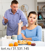 Upset man and frustrated woman arguing at home kitchen. Focus on woman. Стоковое фото, фотограф Яков Филимонов / Фотобанк Лори
