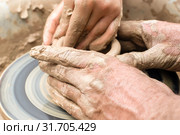 Two pairs of hands mold something from clay on a potter's wheel. Стоковое фото, фотограф Евгений Харитонов / Фотобанк Лори
