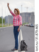 Mature woman waving hand for stop the car, standing in the middle of urban road. Стоковое фото, фотограф Кекяляйнен Андрей / Фотобанк Лори