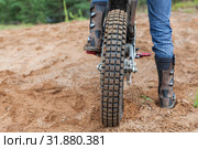 Motorcycle racer with boots standing on peg of dirt bike on sandy track. Стоковое фото, фотограф Кекяляйнен Андрей / Фотобанк Лори