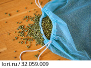 Top view of green mung bean in blue reusable package on wooden background. Healthy eating concept. Стоковое фото, фотограф Ольга Балынская / Фотобанк Лори