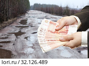 Руки держат российские рубли на фоне старой асфальтированной дороги, полной выбоин, коллаж. Стоковое фото, фотограф Кекяляйнен Андрей / Фотобанк Лори