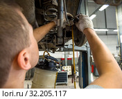Автомеханик подключает прибор для замены тормозной жидкости к штуцеру барабана (2019 год). Редакционное фото, фотограф Вячеслав Палес / Фотобанк Лори